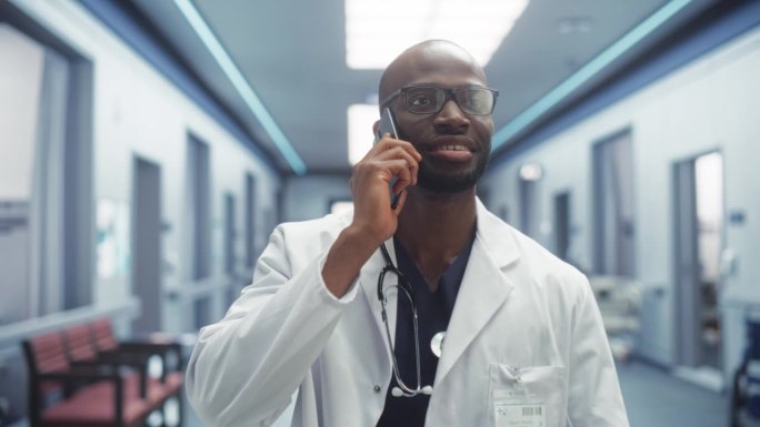 医院病房走廊:乐于助人的黑人男医生与病人通话，给出药物建议的肖像。医生边走边说他的智能手机，远程咨询