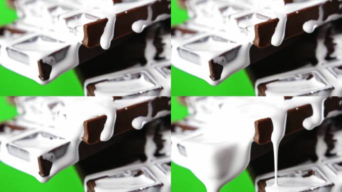 巧克力与白奶油的特写。股票剪辑。白色的液体奶油顺着巧克力棒流下来。甜巧克力与奶油在绿色背景。