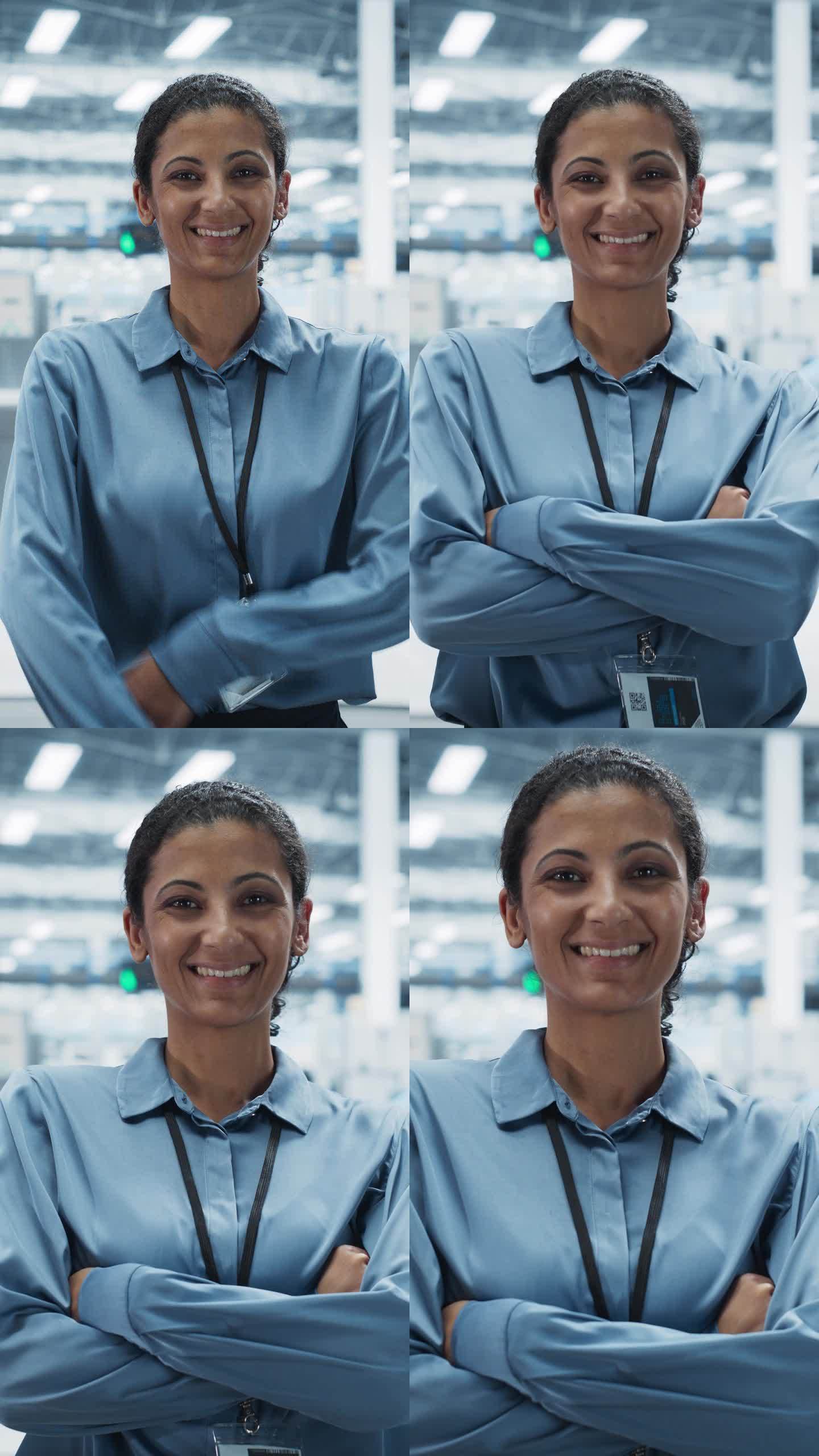 垂直屏幕:西班牙裔女性设施经理的肖像，双臂交叉站着，看着摄像机，微笑着。在一家自动电子厂生产电脑的专