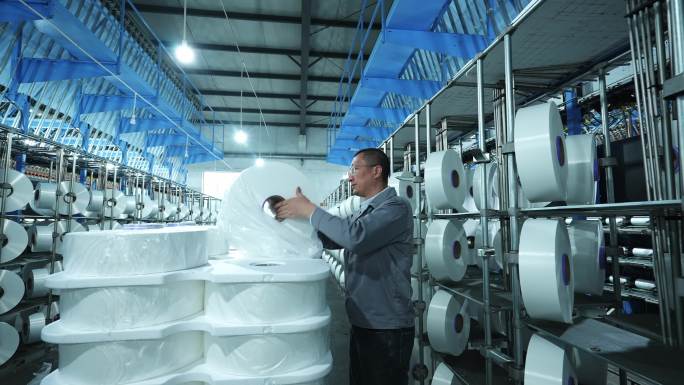 男性纺织工人在化纤纺织厂车间工作