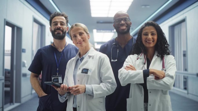 医疗团队:一名成功的不同医疗专业人员的团队肖像，他们站在现代医院办公室里，摆姿势，看着镜头，微笑