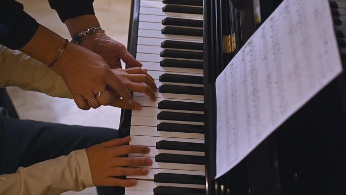 音乐家老师和男孩的手指触摸钢琴琴键，捕捉音乐的节奏，弹奏钢琴