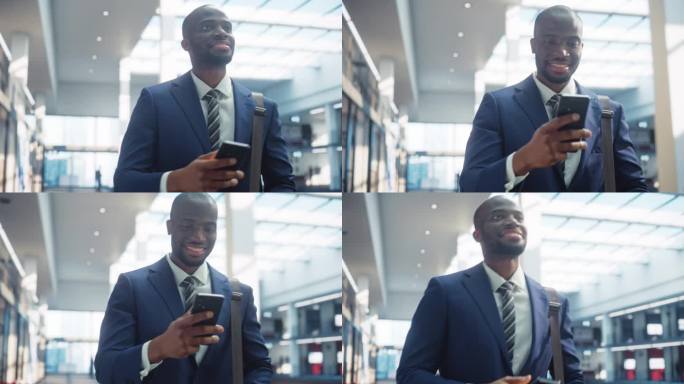 穿着完美剪裁西装的年轻黑人男子的肖像走在公司办公室的走廊上，他微笑着使用智能手机。成功的商人通过电子