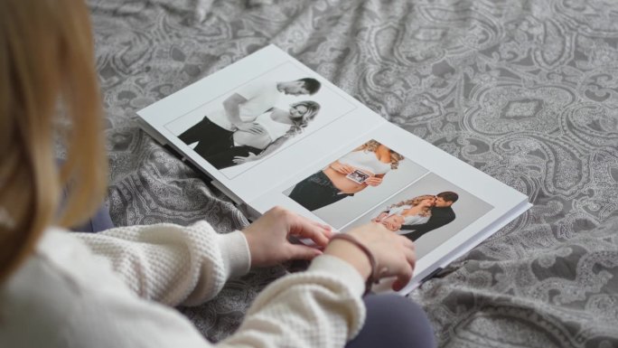 一个十几岁的女孩翻阅一本相册，里面有她爸爸和怀孕妈妈的照片。