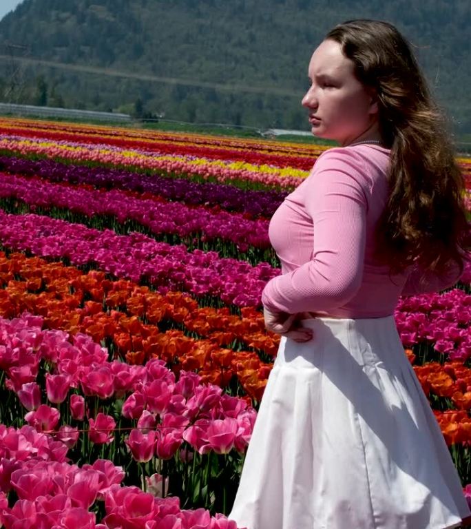 可爱的小女孩，一头长长的卷发，穿着浅粉色的裙子，走在白色和粉红色的风信子之间，在荷兰美丽的彩色风信子