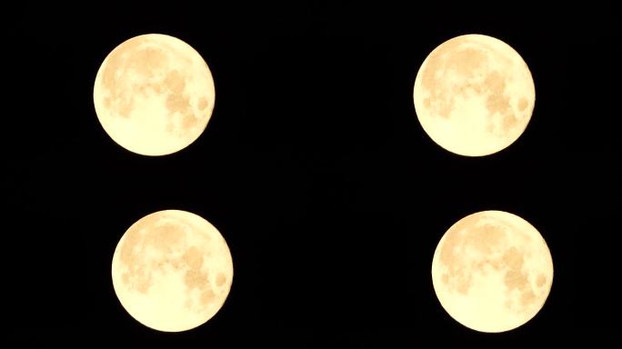 从地球上透过大气层看到的金色满月，映衬着繁星点点的夜空。一轮巨大的满月划过天空，月亮从左边的画面移向