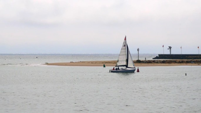 帆船从左到右横跨太平洋到达圣巴巴拉斯特恩斯码头附近的海岸