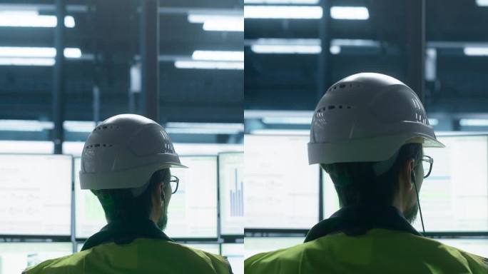 竖屏:白人男工程师用多监控工作站控制机械臂装配线生产的后景特写。制造工艺调整。