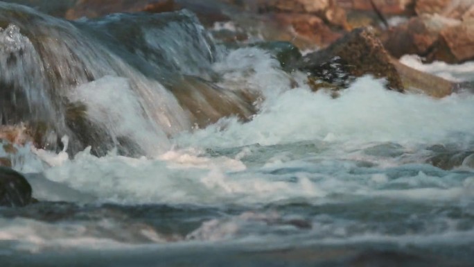 在阳光明媚的夜晚，河流在岩石瀑布上流动，特写细节，相机平移到侧面
