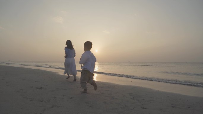 妈妈陪伴孩子沙滩奔跑逆光跑步背影欢乐童年