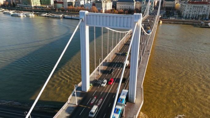 在阳光明媚的日子里，在布达佩斯城市景观的道贝河上伊丽莎白桥上移动的车辆的运动模糊无人机镜头