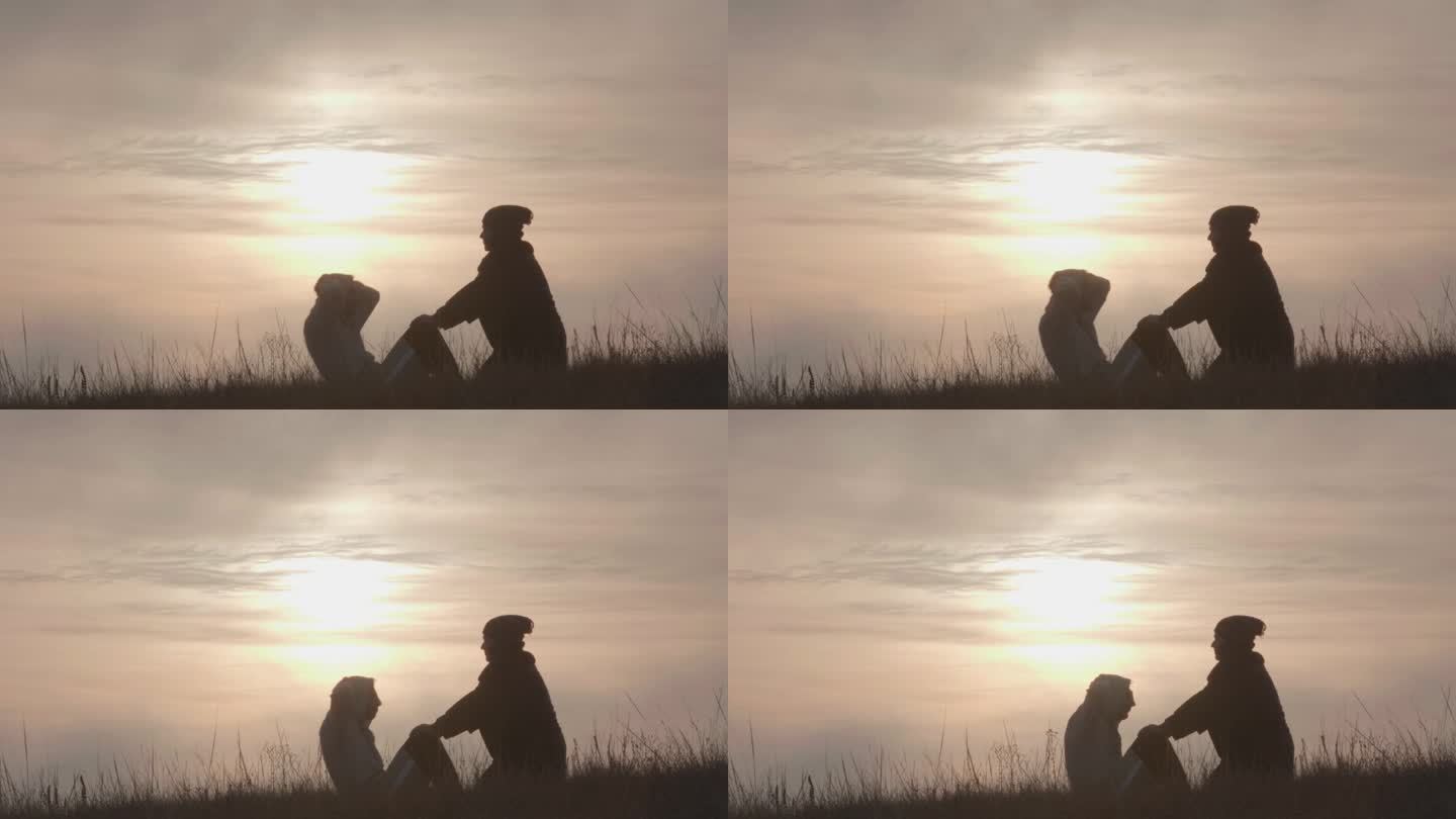 健康的生活方式。一名女子扶着一名男子的膝盖，在日落时被薄雾笼罩的山脉背景下，在干燥的秋草上练习按压肌