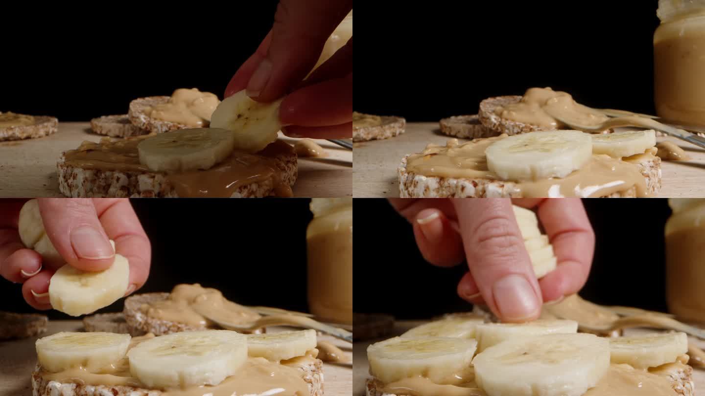 一位妇女把香蕉片放在抹了花生酱的年糕上。多莉滑块极端特写。