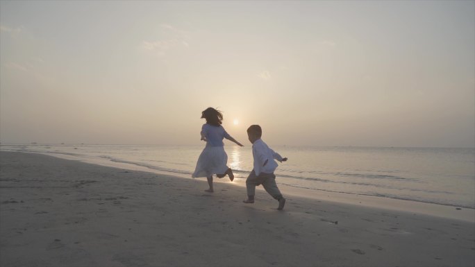妈妈陪伴孩子沙滩张开双臂自由奔跑人物背影