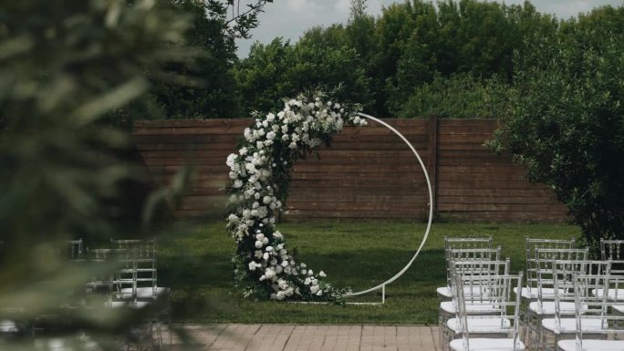 圆形的婚礼拱门上点缀着浅色的花朵