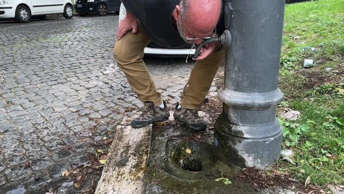 从罗马典型的纳松饮水机饮水的男子:免费的淡水