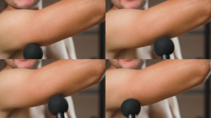 用敲击按摩器锻炼肱三头肌，特写。一个人在锻炼后按摩他的手臂肌肉
