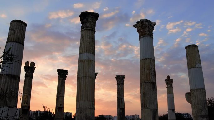戏剧性的日落背景是一个古老的柱廊，一个历史悠久的希腊场景。火红天空下的柱廊废墟，一个概念性的古老景象