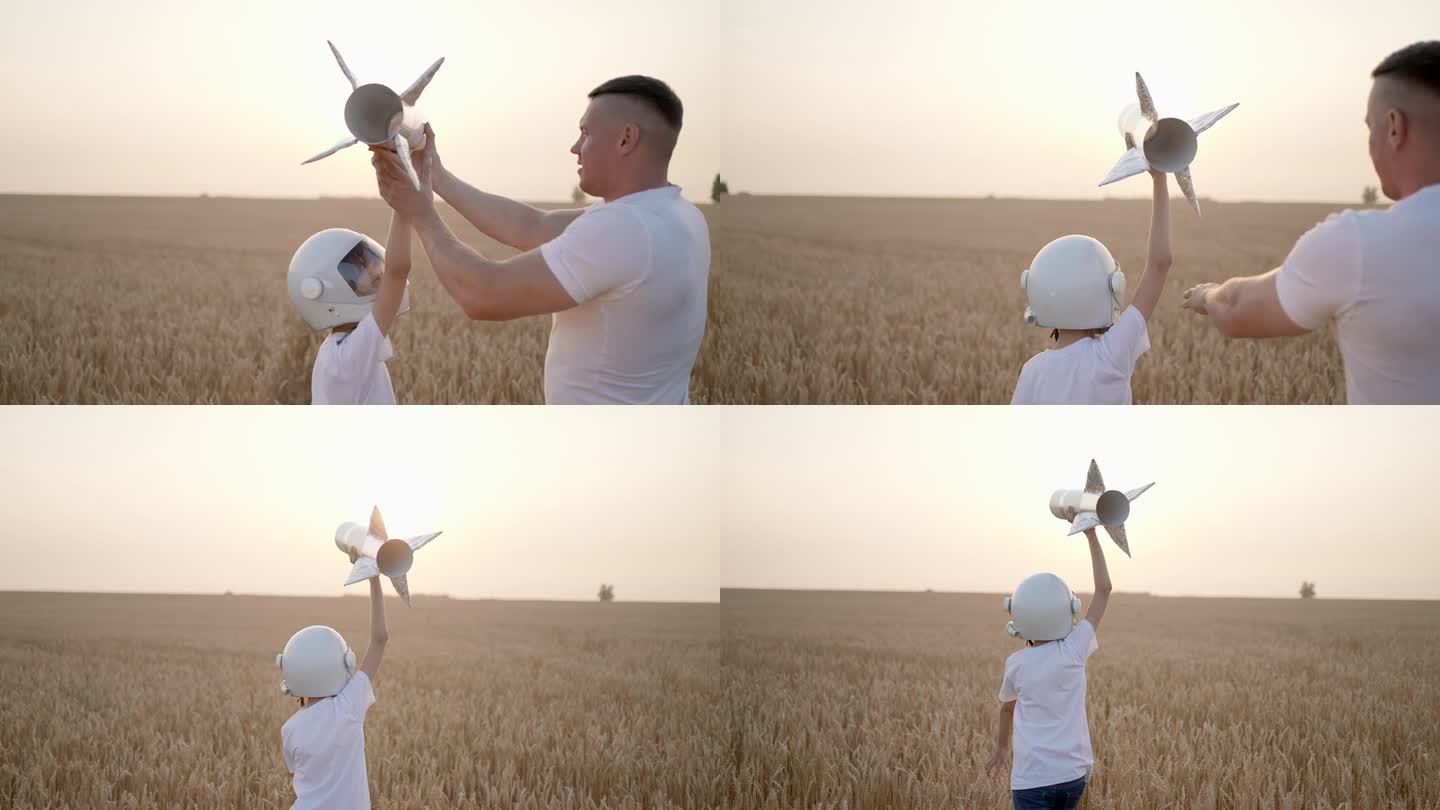 父亲、儿子、男孩、少年在日落的田野里玩着玩具火箭的飞行员、宇航员。孩子大梦想飞行宇航员空间，概念童年