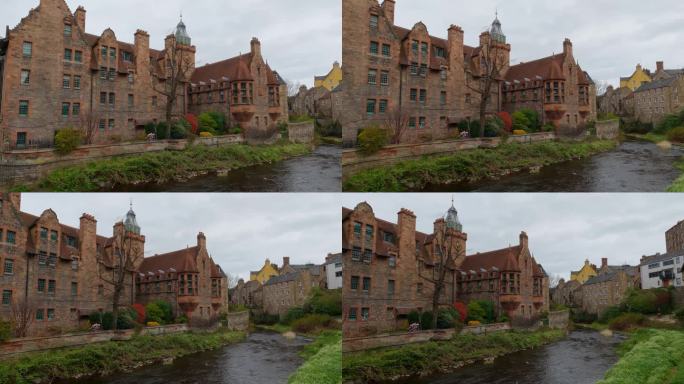 苏格兰爱丁堡砖砌建筑之间的青苔海岸上流动的河流的广角慢镜头