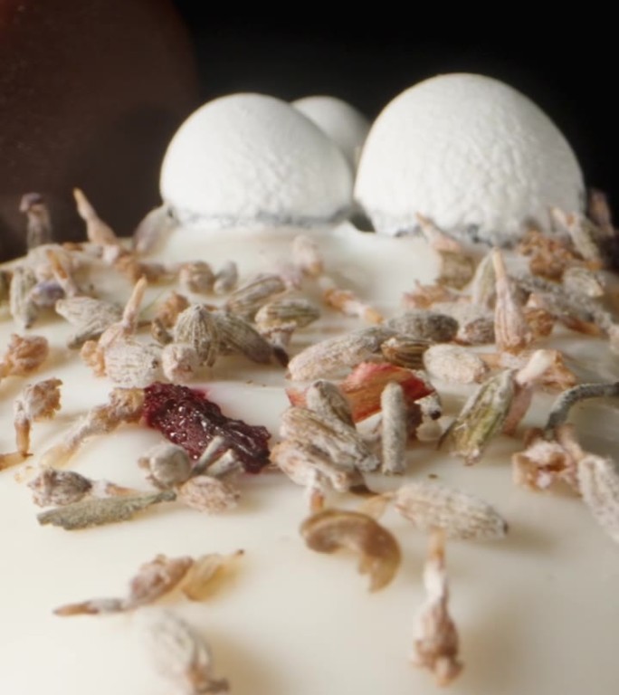 垂直视频。复活节蛋糕，用白色糖霜装饰，上面有心形巧克力和小鸡蛋。多莉滑块极端特写。