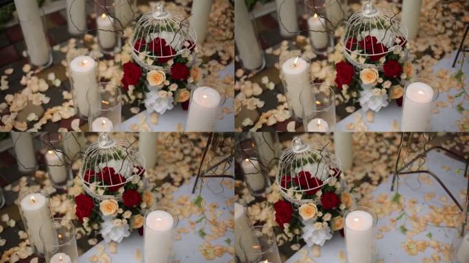 优雅的婚礼装饰以鸟笼里的白玫瑰、红玫瑰、铺满花瓣的地板上的蜡烛、浪漫的活动场景为特色。婚礼插花中心，