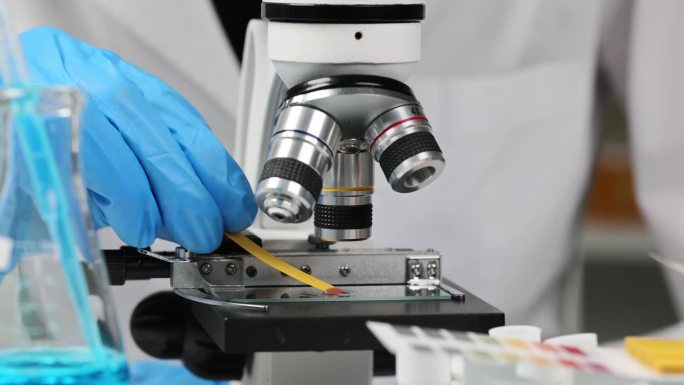 科学家化学家检查酸度的玻璃载玻片附近显微镜使用石碑试纸近距离4k电影慢镜头