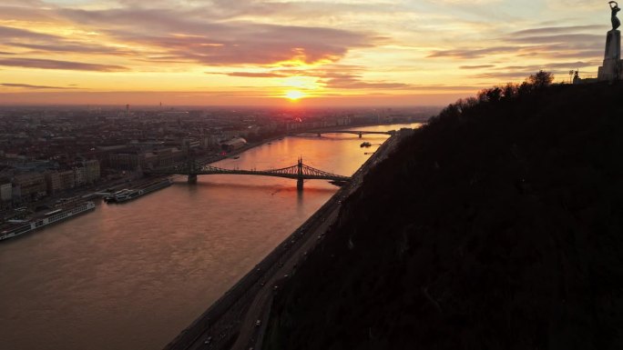 空中无人机拍摄的多瑙河上的自由桥在日落时分的城市剪影中，匈牙利布达佩斯