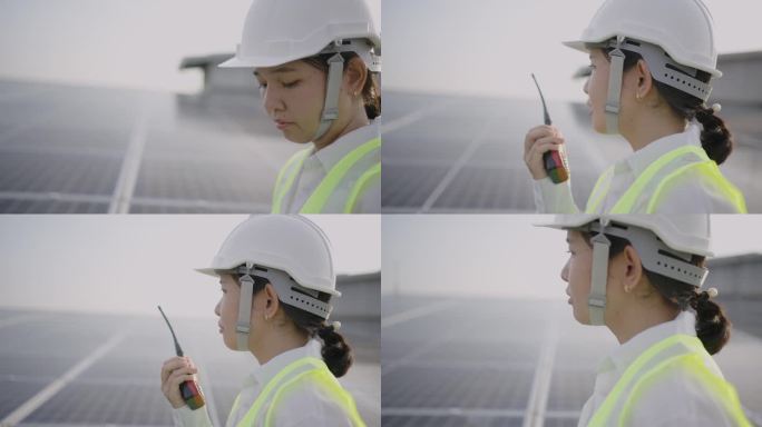 亚洲中年女工程师在太阳能农场使用数字平板电脑，穿着防护服，戴着头盔，通过无线电与她的团队沟通。