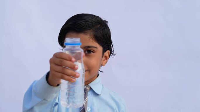 印度学校的孩子们在喝水。一个可爱的孩子从白色的可重复使用的瓶子里喝水