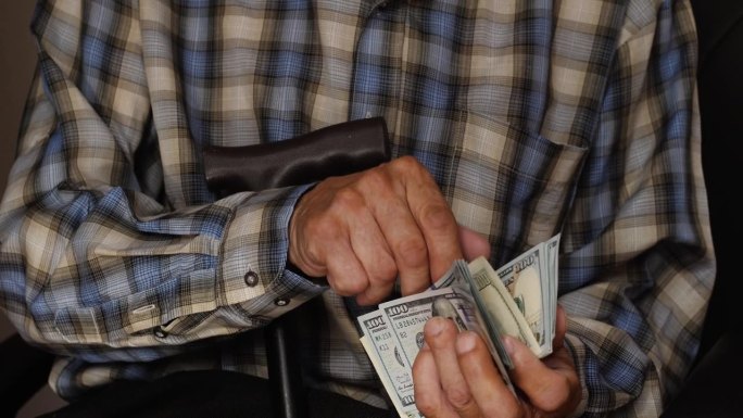 有钱快乐的爷爷用手杖数现金，在家计算内部账目。这个男人对自己的收入很满意，赢了，为计划中的假期和礼物