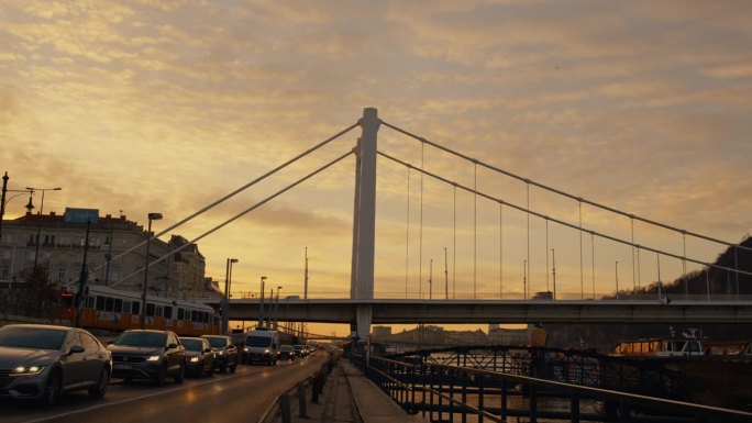 低角度手持拍摄的高伊丽莎白桥在繁忙的道路对天空在日落期间在布达佩斯，匈牙利