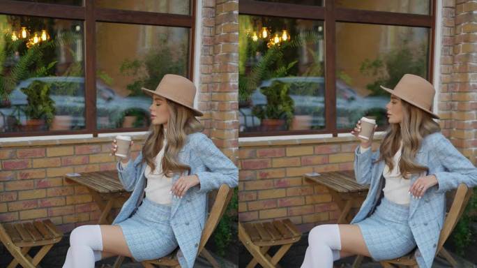 一个年轻的金发女郎在街边的咖啡馆用纸杯喝咖啡