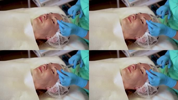 戴着手套的化妆师给女性皮肤注射拉脸针。女顾客在保健所接受美容手术