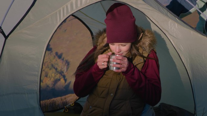 一个女人坐在帐篷里，试着温暖她冻僵的手