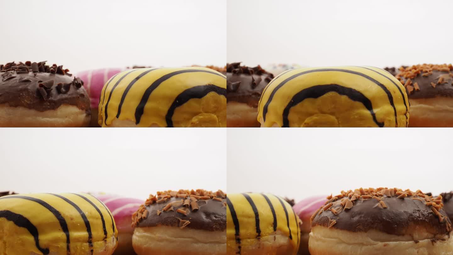 不同口味和颜色的甜甜圈在白色背景上旋转。