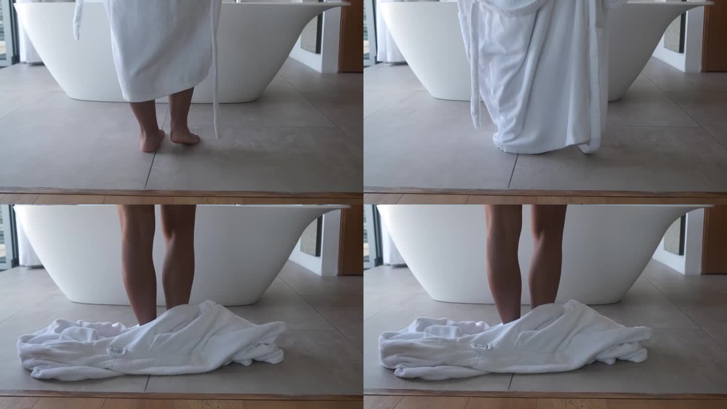 穿着浴袍的女人站在浴室里，腿的特写。