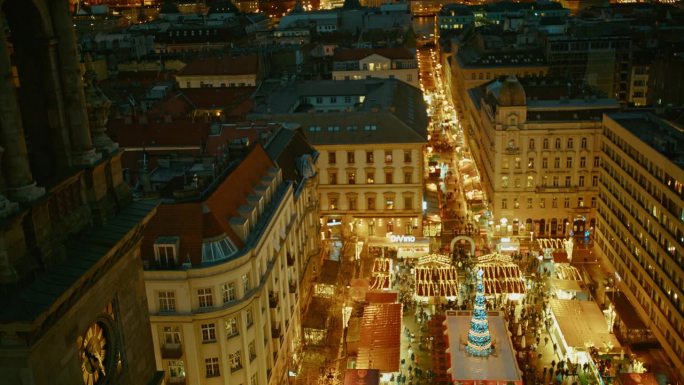 在匈牙利布达佩斯，夜景中，人们在灯火通明的圣诞市场上的空中封锁镜头
