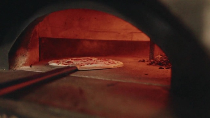 专业披萨师将那不勒斯披萨放入特制烤箱