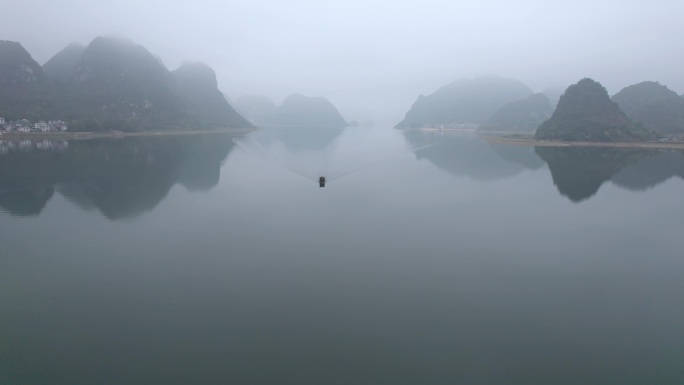 船舶在靖西渠洋湖平静的水面上喀斯特迷雾中