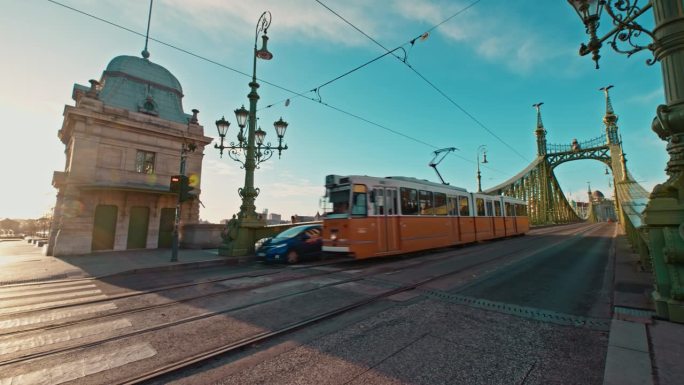 手持拍摄的有轨电车和汽车通过自由桥在晴朗的日子对蓝天在布达佩斯，匈牙利