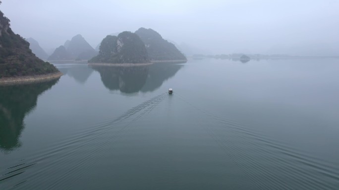 船舶在靖西渠洋湖平静的水面上喀斯特迷雾中