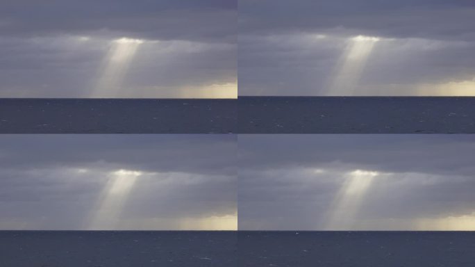 固定拍摄波涛汹涌的多风海洋，戏剧性的光线穿过地平线上的风暴