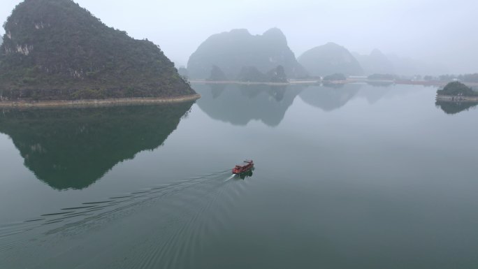 船舶在靖西渠洋湖平静的水面上喀斯特迷雾中