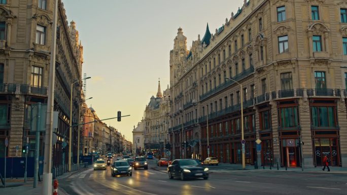 手持拍摄的汽车在城市街道上的历史建筑在黄昏，匈牙利布达佩斯