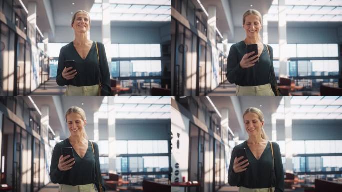 一个快乐的白人女性在她的智能手机上发短信，微笑着走在公司办公室。女性高级营销经理查看社交媒体趋势并保