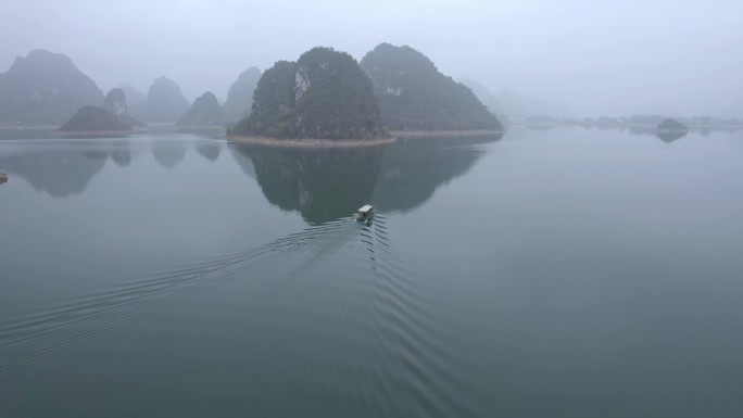 船舶在靖西渠洋湖平静的水面上喀斯特迷雾中