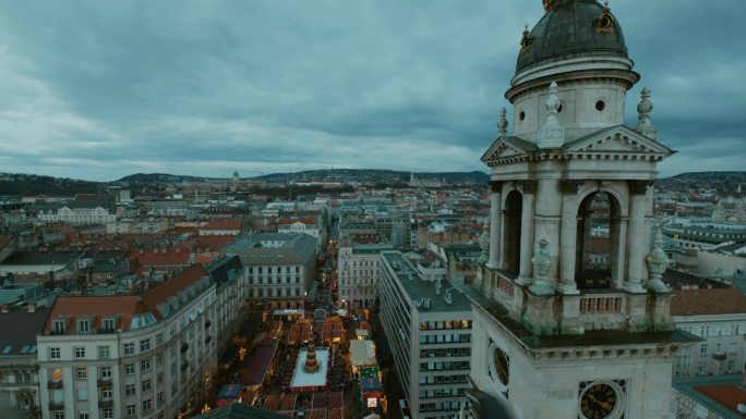 匈牙利，圣斯蒂芬大教堂的钟楼俯瞰布达佩斯的城市景观和圣诞市场，黄昏时天空多云