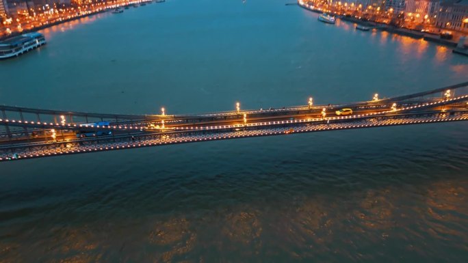放大无人机拍摄的车辆在多瑙河上照亮的szacimchenyi链桥上行驶的黄昏，匈牙利布达佩斯