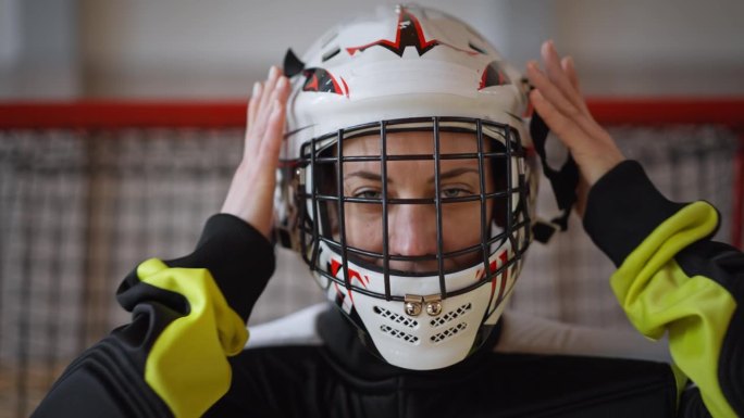 女子地球守门员在健身房戴上头盔准备比赛的特写。